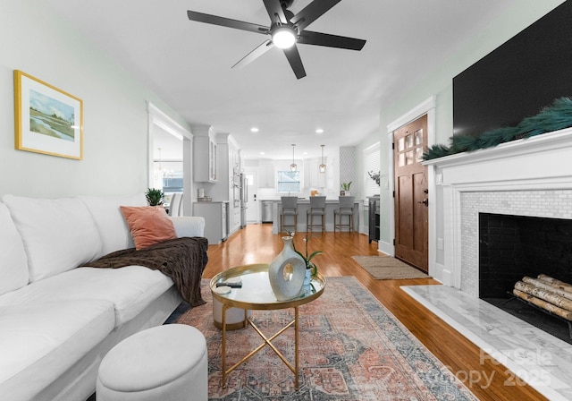 living room with a ceiling fan, recessed lighting, light wood-style floors, and a fireplace