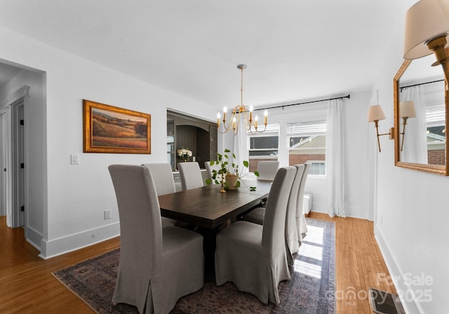 dining room with baseboards, a notable chandelier, visible vents, and light wood-style flooring