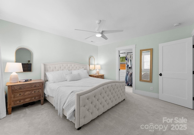 bedroom with light carpet, baseboards, a closet, ceiling fan, and a walk in closet