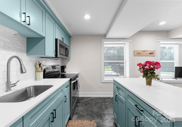 kitchen featuring stainless steel appliances, a sink, baseboards, backsplash, and concrete floors