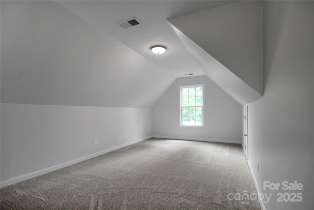 additional living space with baseboards, lofted ceiling, carpet, and visible vents