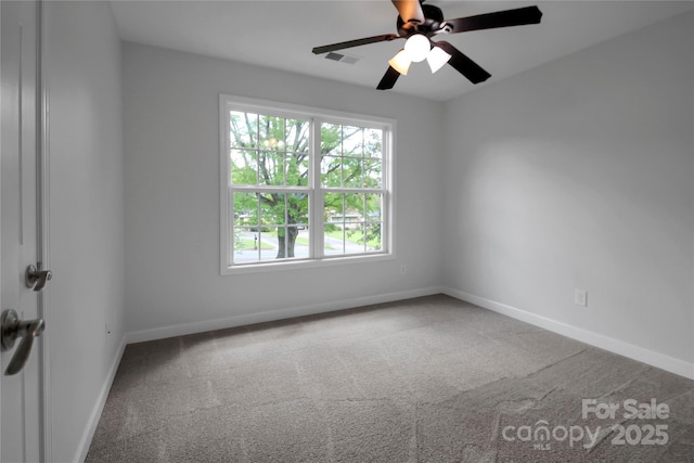 carpeted empty room with baseboards, a ceiling fan, and visible vents