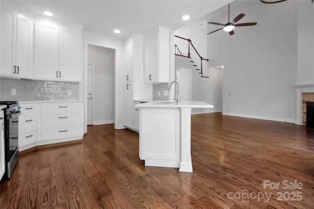 kitchen featuring open floor plan, light countertops, electric range, a ceiling fan, and a sink