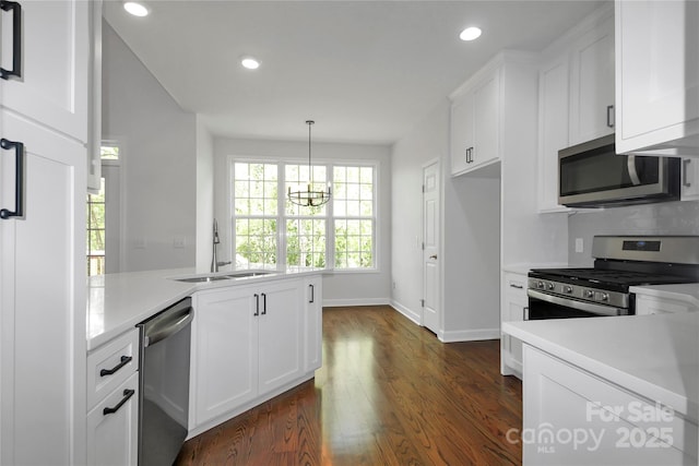kitchen featuring an inviting chandelier, dark wood-style floors, white cabinetry, appliances with stainless steel finishes, and a sink