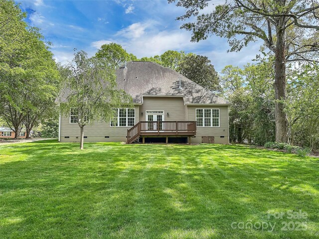 rear view of house with a yard, a wooden deck, a shingled roof, and crawl space