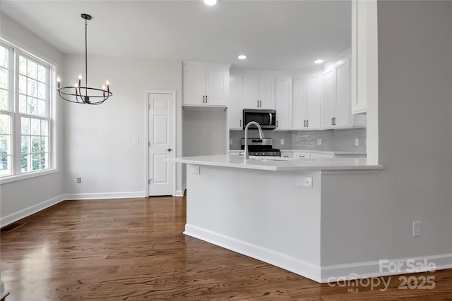 kitchen with appliances with stainless steel finishes, light countertops, white cabinetry, and baseboards