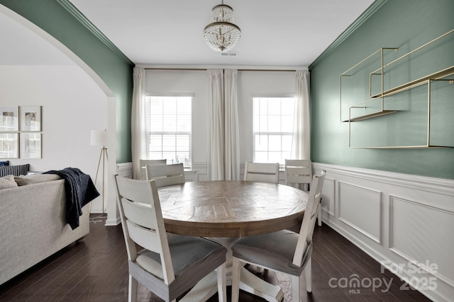 15127 Oleander Dr, Charlotte, NC 28278 - dining area with dark wood-style floors, crown molding, wainscoting, a decorative wall, and arched walkways