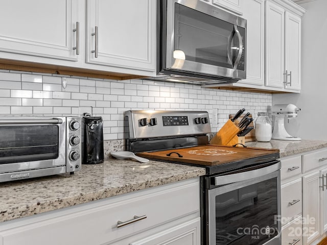 218 Little Man Dr, Boiling Springs, SC 29316 - kitchen featuring light stone counters, a toaster, white cabinetry, decorative backsplash, and stainless steel appliances