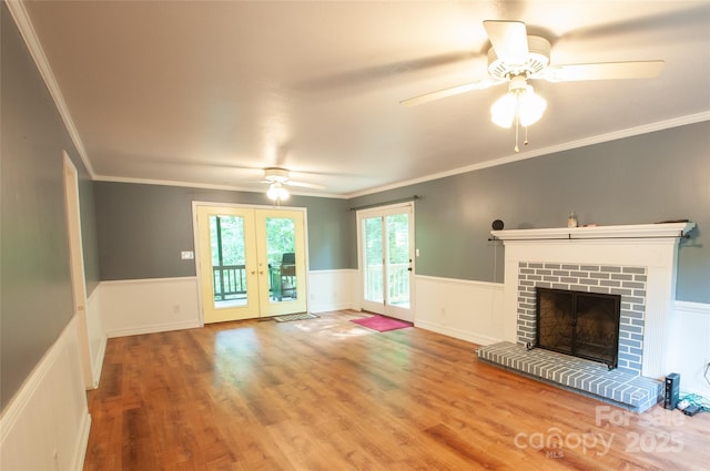 2540 Heritage Cir, Statesville, NC 28625 - unfurnished living room featuring a ceiling fan, a wainscoted wall, a brick fireplace, wood finished floors, and crown molding