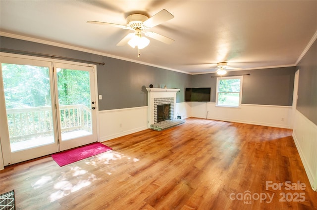 2540 Heritage Cir, Statesville, NC 28625 - unfurnished living room featuring a ceiling fan, wainscoting, wood finished floors, a brick fireplace, and ornamental molding