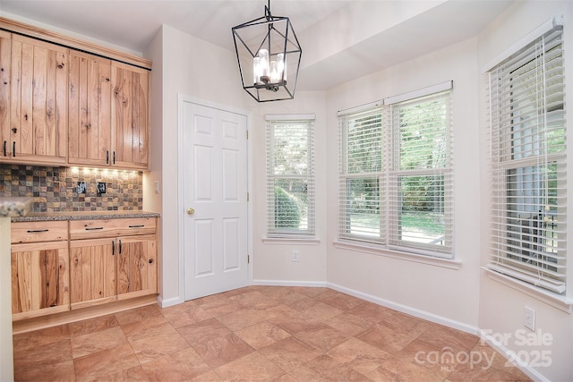 unfurnished dining area featuring plenty of natural light, baseboards, and a chandelier