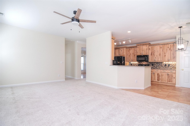 unfurnished living room with track lighting, baseboards, ceiling fan with notable chandelier, and light carpet