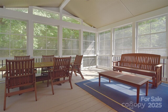 sunroom / solarium featuring vaulted ceiling, a healthy amount of sunlight, and wood finished floors