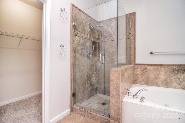 full bath with a stall shower, a garden tub, and a spacious closet