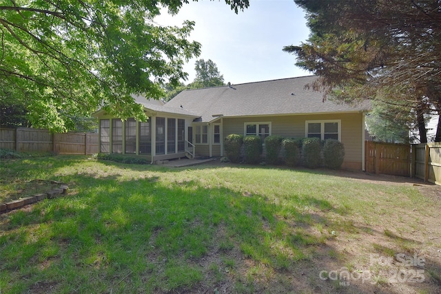 back of house with a fenced backyard, a yard, and a sunroom