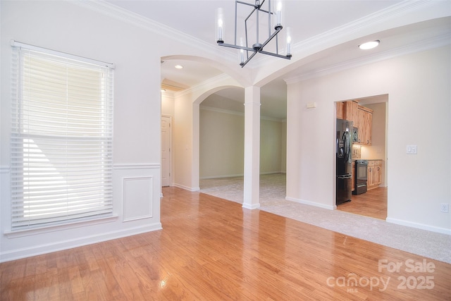unfurnished dining area with crown molding, arched walkways, light wood-style floors, and ornate columns