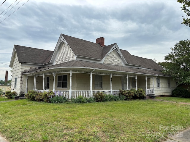 farmhouse inspired home with a front lawn, a shingled roof, covered porch, and a chimney