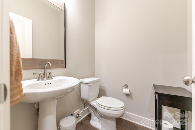 half bathroom featuring baseboards, toilet, and wood finished floors