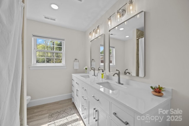 bathroom with visible vents, wood finished floors, a sink, and a healthy amount of sunlight
