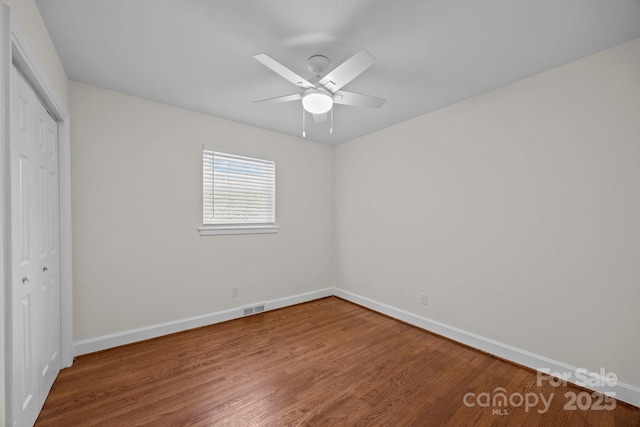 unfurnished bedroom featuring visible vents, baseboards, a ceiling fan, wood finished floors, and a closet