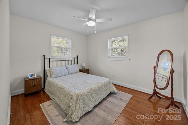 bedroom featuring dark wood finished floors, ceiling fan, baseboards, and multiple windows
