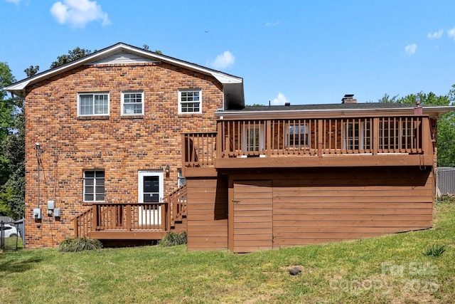 rear view of property with a lawn, a chimney, brick siding, and a deck