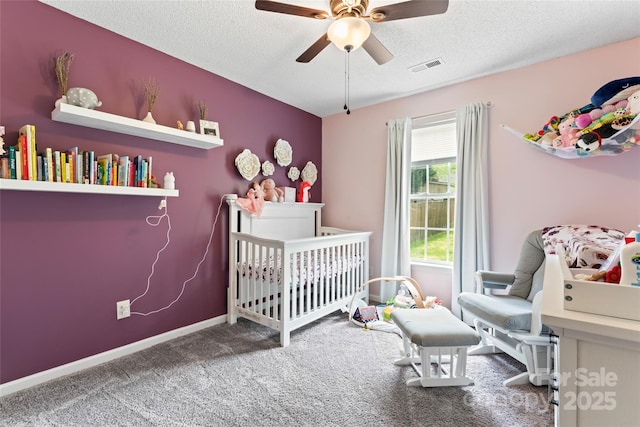 bedroom with carpet, visible vents, a nursery area, baseboards, and a textured ceiling