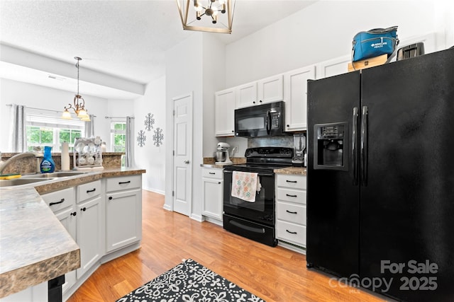 kitchen with white cabinets, light wood-style floors, a sink, and black appliances