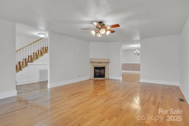 63 Frost Ln, Taylorsville, NC 28681 - unfurnished living room featuring light wood-type flooring, a ceiling fan, stairway, a tile fireplace, and baseboards
