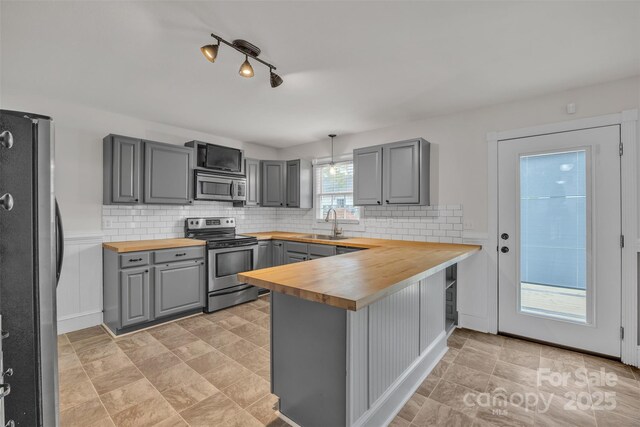 63 Frost Ln, Taylorsville, NC 28681 - kitchen featuring butcher block countertops, appliances with stainless steel finishes, gray cabinetry, a peninsula, and a sink