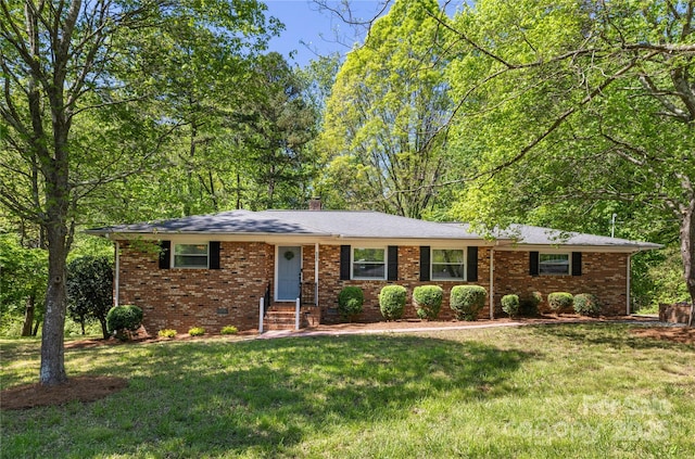 ranch-style home featuring a chimney, brick siding, entry steps, and a front yard