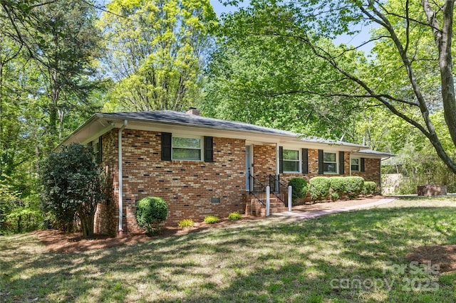 view of front of property with brick siding, a chimney, and a front lawn