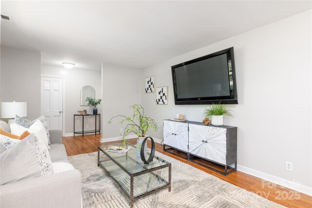 living room with baseboards, wood finished floors, and visible vents