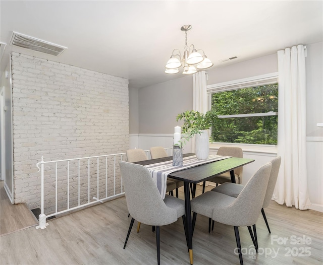 dining room featuring wainscoting, a notable chandelier, wood finished floors, and visible vents