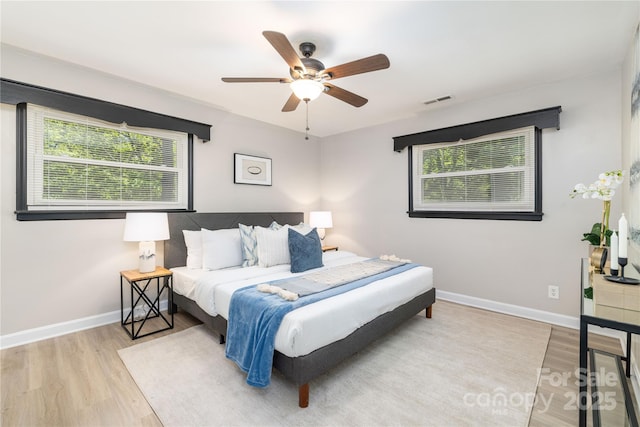 bedroom featuring visible vents, baseboards, wood finished floors, and multiple windows