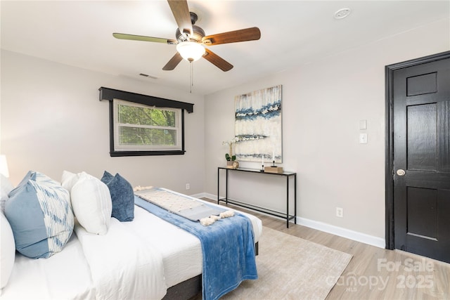 bedroom featuring wood finished floors, visible vents, a ceiling fan, and baseboards