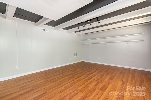 interior space with rail lighting, wood finished floors, visible vents, and baseboards