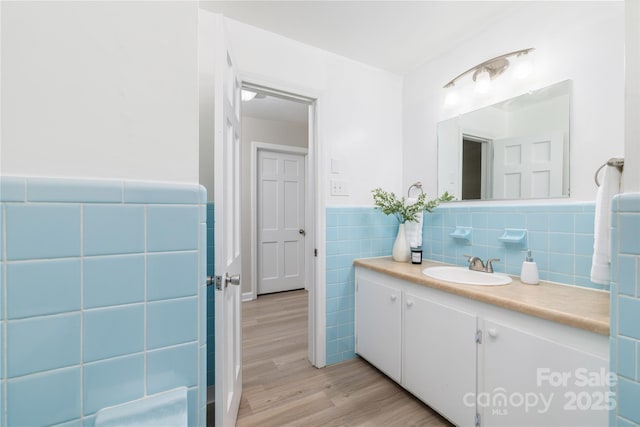 bathroom with wainscoting, vanity, wood finished floors, and tile walls