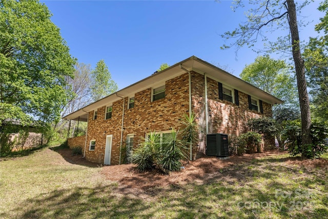 view of home's exterior featuring brick siding, a yard, and cooling unit