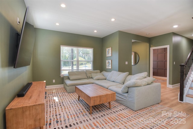 living area featuring recessed lighting, baseboards, stairs, and light wood-style flooring