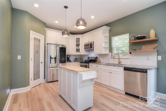 kitchen with open shelves, a sink, stainless steel appliances, white cabinetry, and tasteful backsplash