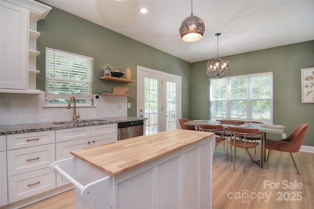 kitchen with stainless steel dishwasher, open shelves, a sink, butcher block counters, and white cabinetry