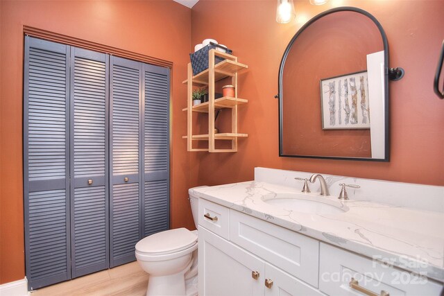 bathroom with toilet, a closet, and vanity
