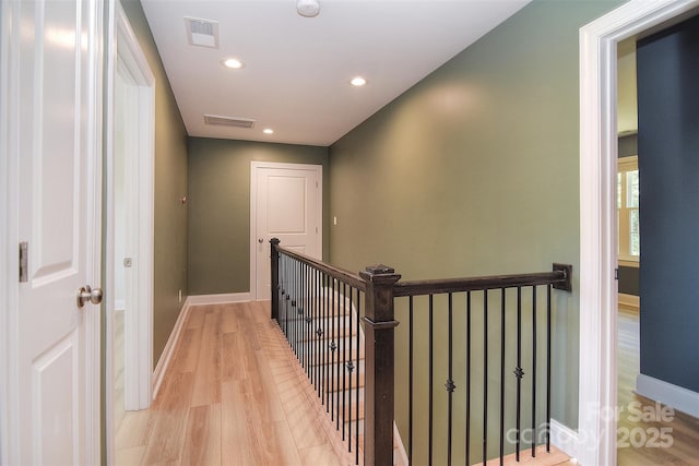 hall with light wood-type flooring, recessed lighting, baseboards, and an upstairs landing
