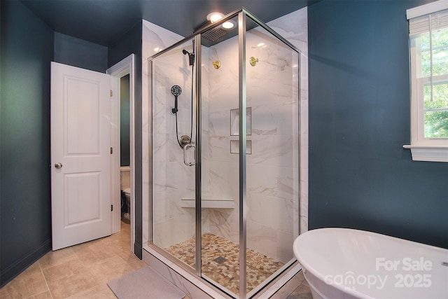 full bathroom featuring baseboards, a freestanding tub, toilet, and a shower stall
