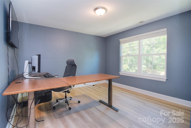 office area with baseboards, light wood finished floors, and visible vents