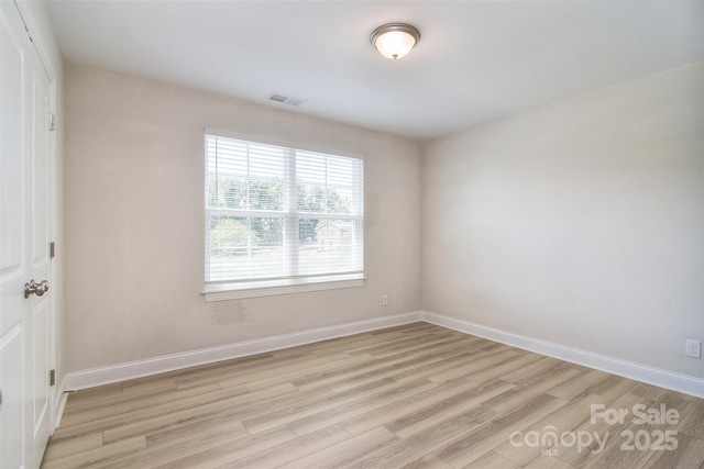 unfurnished room featuring baseboards, light wood-style flooring, and visible vents