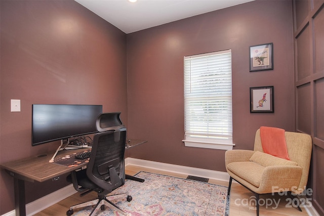 office featuring baseboards, visible vents, and wood finished floors