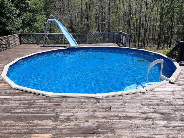 541 Pilgrim Rd, Ellenboro, NC 28040 - pool featuring a view of trees, a water slide, and a deck