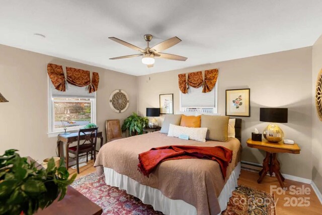 88 S Main St, Weaverville, NC 28787 - bedroom featuring a baseboard heating unit, baseboards, a ceiling fan, and wood finished floors